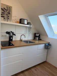 a kitchen with white cabinets and a sink and a window at Deich Winde 9.1 in Dorum-Neufeld