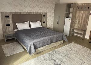 a bedroom with a large bed and a refrigerator at KOLESEY Hotel in Taldykorgan