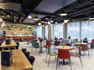 a restaurant with tables and chairs and windows at ibis Styles Bern City in Bern