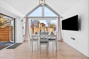 a dining room with a table with chairs and a tv at The Oak Sty - 2 Bed Countryside Cottage Escape in Durley with Hot Tub, Unique rural retreat, Private Parking, Sleeps 4 & Pet friendly - By Blue Puffin Stays in Southampton