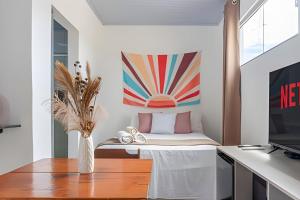 a room with a bed with a vase on a table at Recanto Sol da Chapada | Aptos no Centro com Garagem e Café da Manhã in Alto Paraíso de Goiás