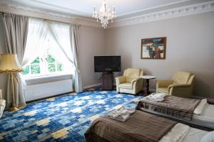 a room with a bed and two chairs and a tv at Hotel Dwór Sójki in Sójki