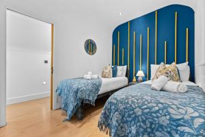 a bedroom with two beds and a large blue headboard at The Oak Sty - 2 Bed Countryside Cottage Escape in Durley with Hot Tub, Unique rural retreat, Private Parking, Sleeps 4 & Pet friendly - By Blue Puffin Stays in Southampton