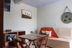a living room with a bed and a table and a desk at Recanto Sol da Chapada | Aptos no Centro com Garagem e Café da Manhã in Alto Paraíso de Goiás