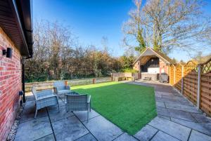 a patio with chairs and a lawn at The Oak Sty - 2 Bed Countryside Cottage Escape in Durley with Hot Tub, Unique rural retreat, Private Parking, Sleeps 4 & Pet friendly - By Blue Puffin Stays in Southampton