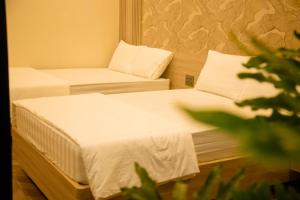 two beds in a room with white sheets and pillows at Mia Hotel Cửa Lò in Vinh