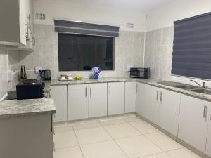 a kitchen with white cabinets and a window at Blue Crane Guesthouse in Hilton