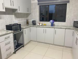 a kitchen with white cabinets and a window at Blue Crane Guesthouse in Hilton +10 photos