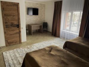 a bedroom with a door and a desk and a window at KOLESEY Hotel in Taldykorgan