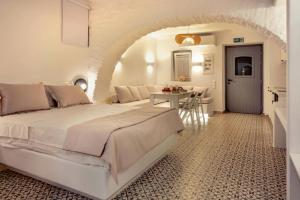 a white bedroom with a bed and a table at Suite Amalaya Κατώι in Kithnos