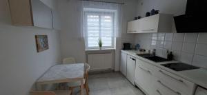 a kitchen with white cabinets and a table and a window at 91 kroków - 91 steps free parking in Bolesławiec