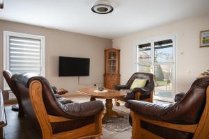 a living room with leather chairs and a tv at Jacuzzi, BBQ & EV plug - 5BR Villa Villi with Garden in Limbuš
