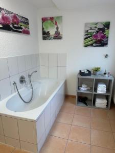 a bath tub in a bathroom with two pictures on the wall at Steinlachquartier in Dußlingen