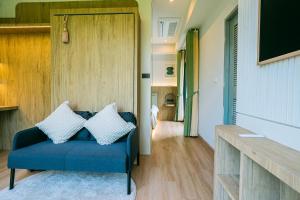 a living room with a blue couch and a tv at Tabebuia House ทาเบบูย่าเฮ้าส์ in Pathiu