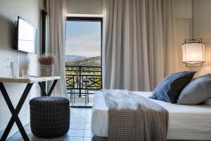 a bedroom with a bed and a balcony with a view at Kefalonia Grand in Argostoli