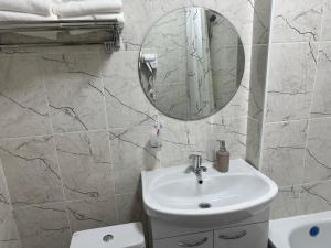 a white bathroom with a sink and a mirror at KOLESEY Hotel in Taldykorgan