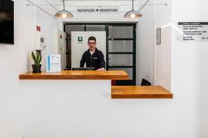 a man sitting at a desk in an office at HI Castelo Branco - Pousada de Juventude in Castelo Branco