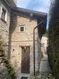a stone house with a brown door and a stairs at House A73 in Lezzeno