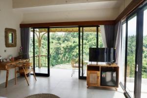 a living room with a tv and a large window at Jungle Valley Villas in Susut
