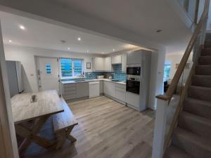 a kitchen with white cabinets and a wooden table at Beachcomber in Croyde