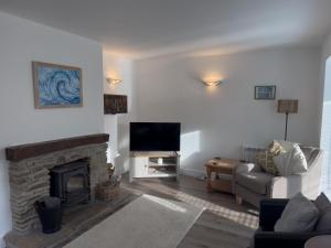 a living room with a fireplace and a tv at Beachcomber in Croyde