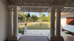 a porch with columns with a view of a park at Tamarind Villa in Kelaniya