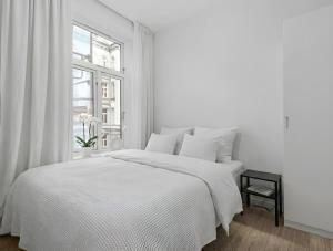 a white bedroom with a white bed and a window at Prime Central Oslo - Frogner, All-Inclusive Apartment in Oslo