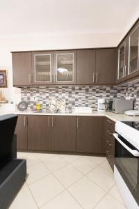 a kitchen with brown cabinets and a tile wall at Nikorina apts in Lefkada