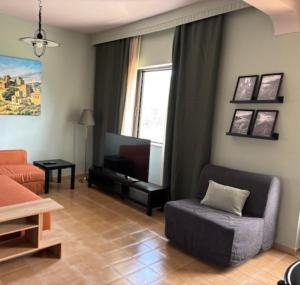 a living room with a couch chair and a television at Dream Village Mani in Karvelás