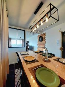 a dining room with a large wooden table with green plates at Appartement à Limoges, proche CHU in Limoges