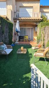 a patio with chairs and an umbrella on the grass at Casa Mistral in Palamós
