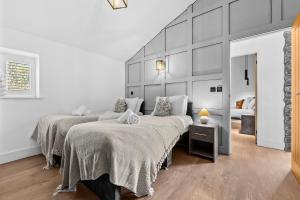 two beds in a room with white walls at The Oaks Barn - A Countryside Luxury Rural Escape with Hot tub & Fire Pit! Tranquil Group Retreat - Sleeps 8, Pet Friendly & Off road Parking - By Blue Puffin Stays in Southampton