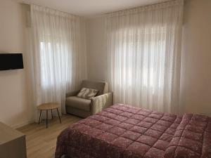 a bedroom with a bed and a chair and a window at Cygnus Bed & Breakfast in Lido di Jesolo
