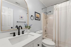 a bathroom with a sink and a toilet and a mirror at Sea Swept Cottage OBX in Kill Devil Hills +27 photos