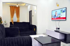 a living room with two black couches and a tv at New Benin Home in Benin City