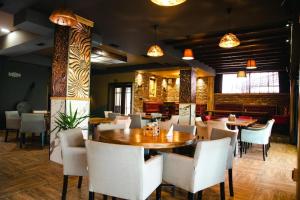 a restaurant with a wooden table and white chairs at Hotel & Restaurant Carevoselski in Delčevo