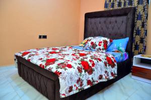 a bedroom with a bed with a floral comforter at New Benin Home in Benin City +26 photos