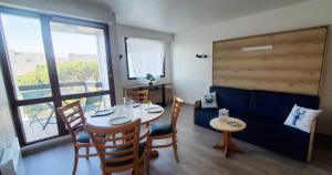 a dining room with a table and chairs and windows at BLEUE OCEANE - Studio, Piscine commune - U65 in Carnac