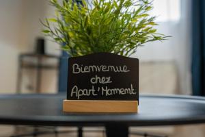 a blackboard sign on a table with a potted plant at Appartement Centre Saint-Omer, Parking privé gratuit in Saint-Omer