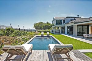 a house with a swimming pool and two chairs at Table Mountain and Constantiaberg view in Sweet Valley