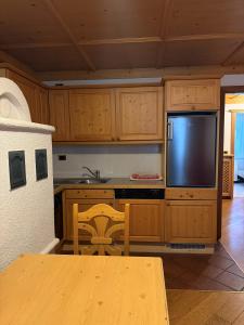 a kitchen with wooden cabinets and a table and a television at Campiglio Bilocale Dolomiti in Madonna di Campiglio
