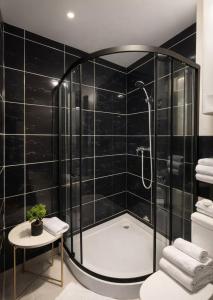 a black tiled bathroom with a shower and a tub at Panorama H2O Self Check-in Pool in Korosten