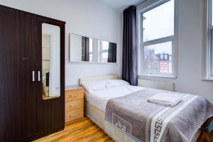 a bedroom with a bed and a dresser and a window at London Brompton Residence Hotel in London
