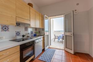 a kitchen with wooden cabinets and a view of the ocean at SeaSide Paradise - Seafront Terrace Apartment by BariHouses in Cozze