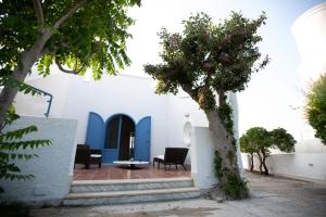 a white building with blue doors and trees at SeaSide Paradise - Seafront Terrace Apartment by BariHouses in Cozze
