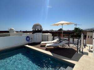 a swimming pool on the roof of a house with an umbrella at Atico duplex con piscina privada, solárium y barbacoa in Vera