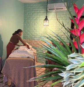 a woman making a bed in a room with a plant at Hotel Casa Grande Gravatá in Gravatá