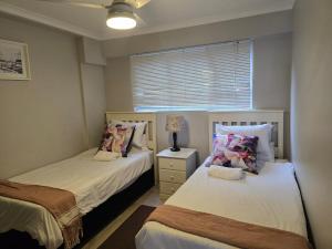 a bedroom with two beds and a lamp and a window at Flat 108 Cozumel, Umdloti Beach Front in Umdloti