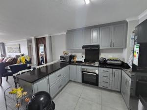 a kitchen with white cabinets and a black counter top at Flat 108 Cozumel, Umdloti Beach Front in Umdloti