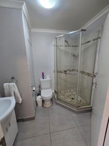 a white bathroom with a shower and a toilet at Flat 108 Cozumel, Umdloti Beach Front in Umdloti +10 photos